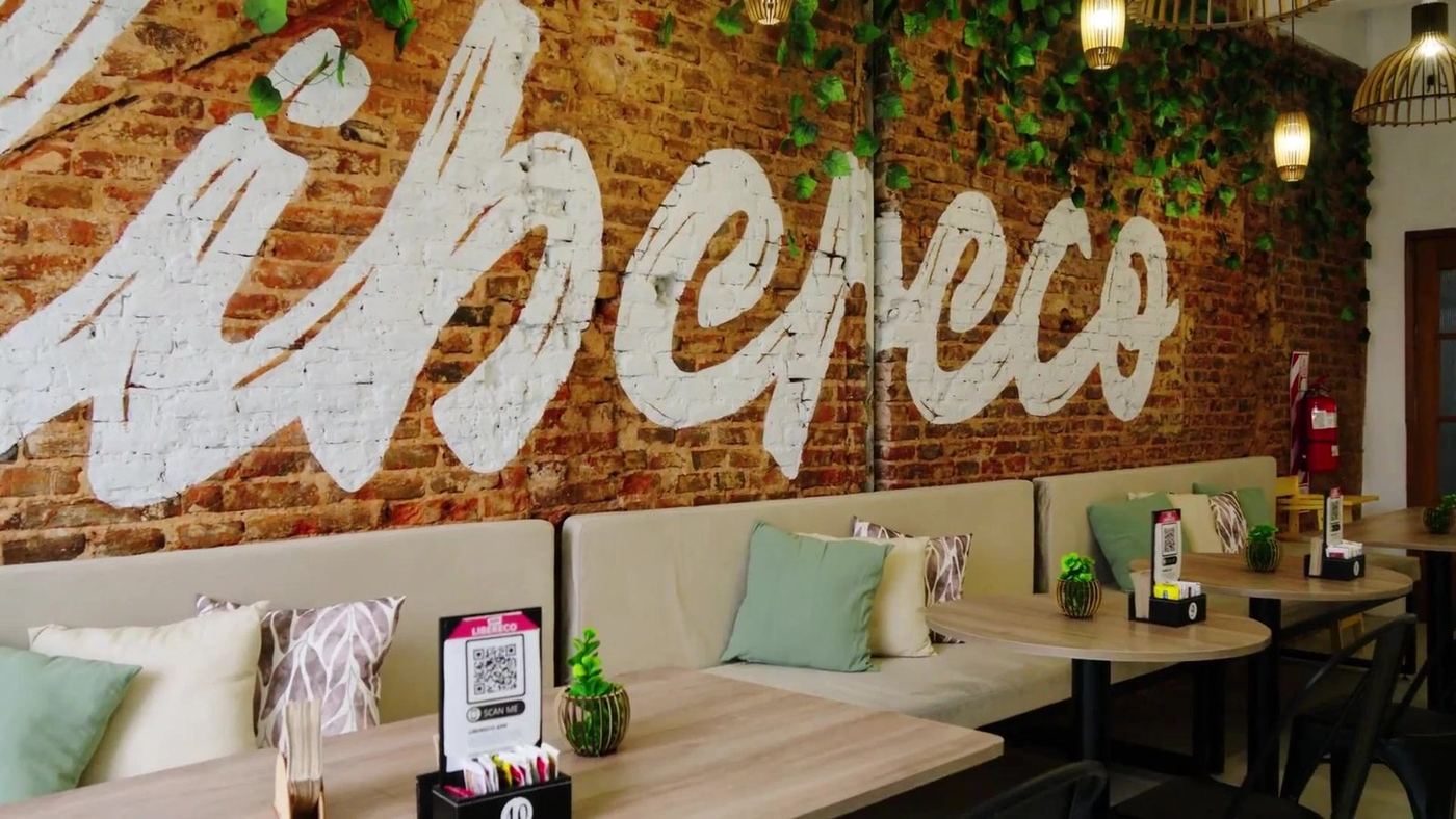 Salón de una heladería Libereco con el logo pintado en la pared de ladrillo